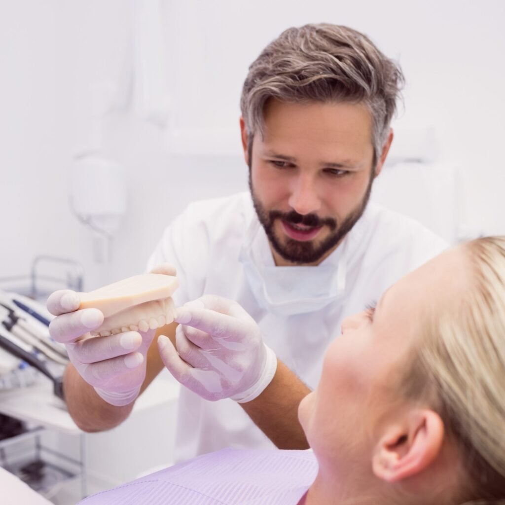 dentist showing denture model patient scaled 1